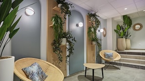 A modern interior with wicker chairs, a wooden wall, and potted plants.