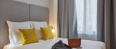 A neatly made bed with pillows, a book, and a handbag on it.