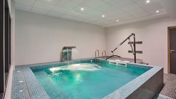Una piscina interior moderna con agua cristalina, un vestuario y una puerta a la derecha.