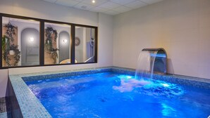 A spa area with a hot tub, a waterfall feature, and a large mirror reflecting the room. - Appart'hôtel Odalys City - Nîmes Arènes - Palais des Congr ès (Nîmes)