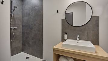 Ein modernes Badezimmer mit Dusche, Waschbecken und Spiegel.