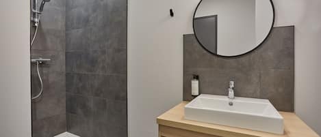 Une salle de bain moderne avec une douche, un lavabo et un miroir.