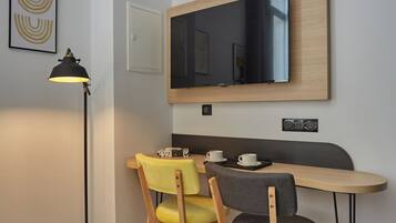Una habitación moderna con escritorio, dos sillas, una lámpara de pie y un espejo grande en la pared.