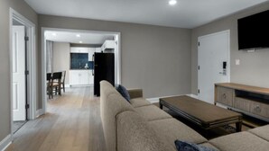 Una sala de estar moderna con un sofá, una mesa de centro y un televisor montado en la pared.