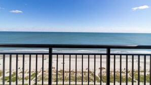 A beach view from a balcony with a railing, sandy beach, and ocean. - Escape to Luxury: 11th Floor Oceanfront Suite (Myrtle Beach)