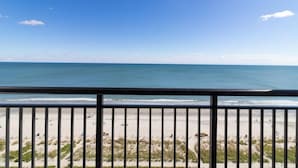 Vista sulla spiaggia dal balcone, con ringhiera, spiaggia sabbiosa e mare.