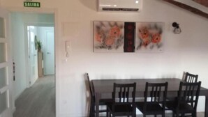 A dining area with a table and chairs, an air conditioning unit, and a door marked 'SALIDA'. - Apartamento Ático, ideal familias y amigos cerca de Senda Viva y Bardena Real. (Arguedas)