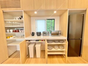 A compact kitchen with wooden cabinets, a built-in oven, a toaster, and a refrigerator.