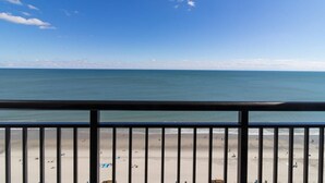 A beach view from a balcony with a railing, sandy beach, and clear blue sky. - 18th Floor, Breathtaking View: Deluxe One Bedroom (Myrtle Beach)