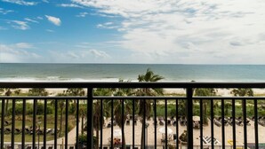 A beach view from a balcony with a railing, palm trees, and beach chairs. - Sunrise to Sunset: 4th Floor Oceanfront Getaway (Myrtle Beach)