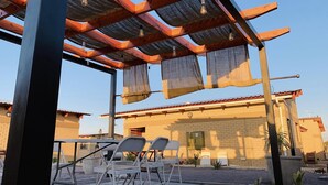 Een terras met metalen stoelen en een pergola.