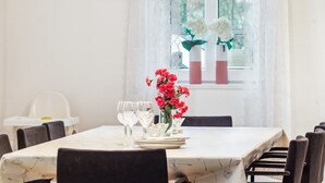 A dining area with a table set for four, white tablecloth, and two vases with flowers.