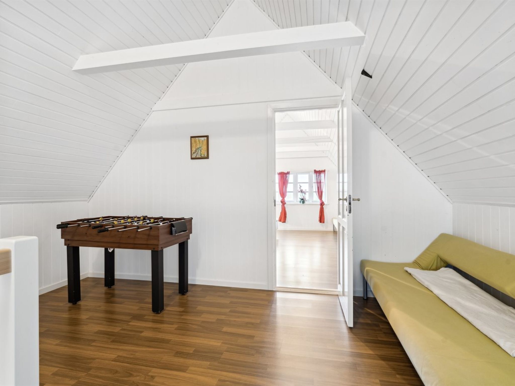 Une pièce avec une table de baby-foot, un canapé et une porte donnant sur une autre pièce.