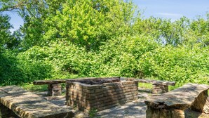 An outdoor seating area with stone benches and a brick fire pit.
