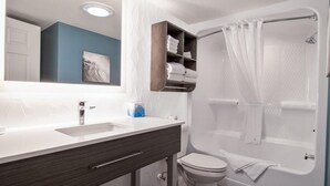 A modern bathroom with a white sink, dark wooden vanity, a white toilet, and a shower with a white curtain.