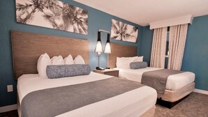 Ein Hotelzimmer mit zwei Betten, einem Holzkopfteil, einem Nachttisch, einer Lampe und Bildern an den Wänden.