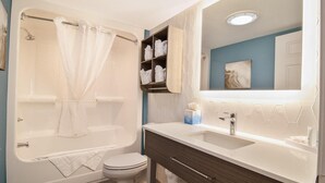 Ein modernes Badezimmer mit Badewanne, Toilette, Waschtisch und einem großen Spiegel.