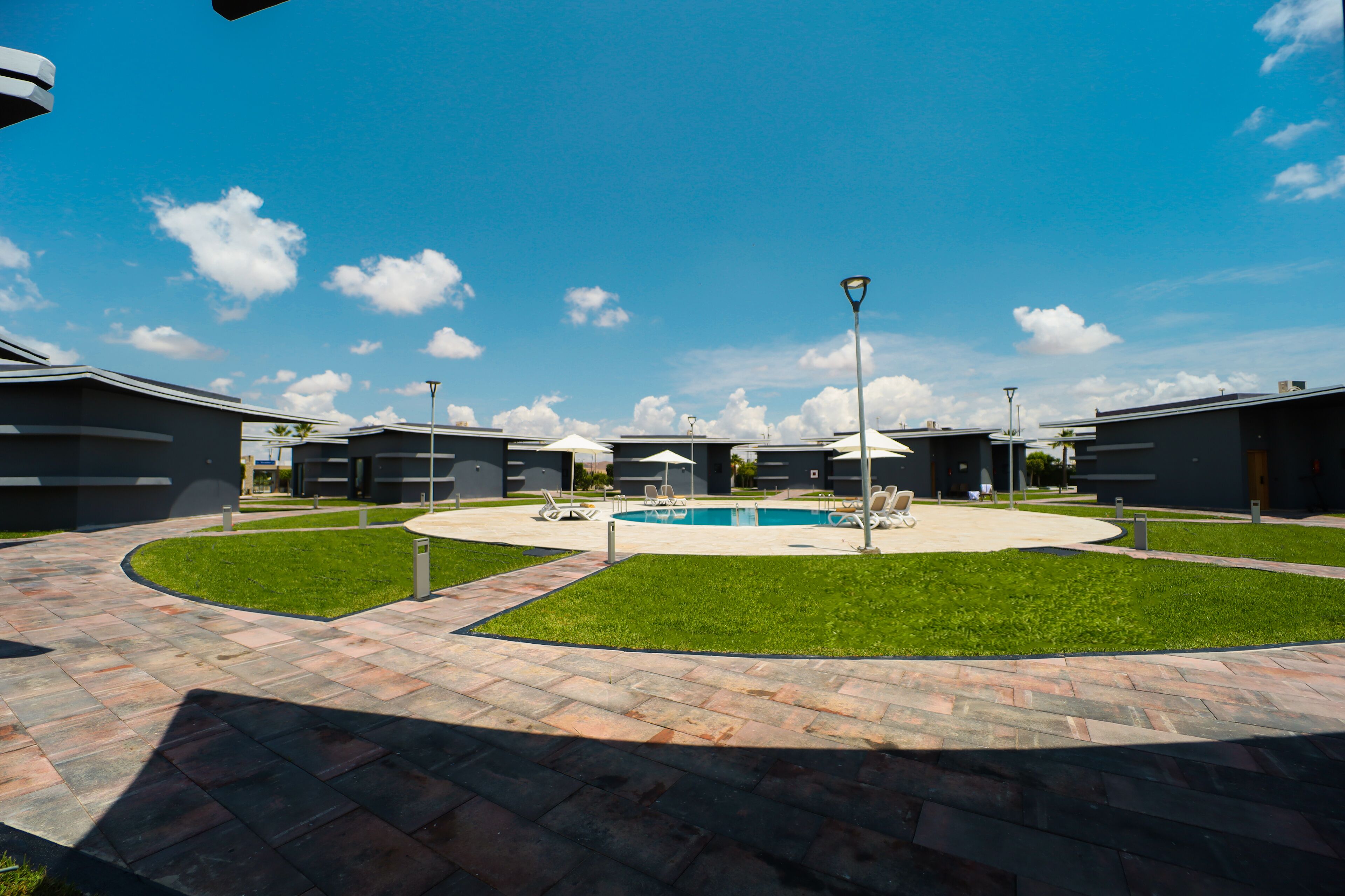 A courtyard with a swimming pool, lounge chairs, and modern buildings.