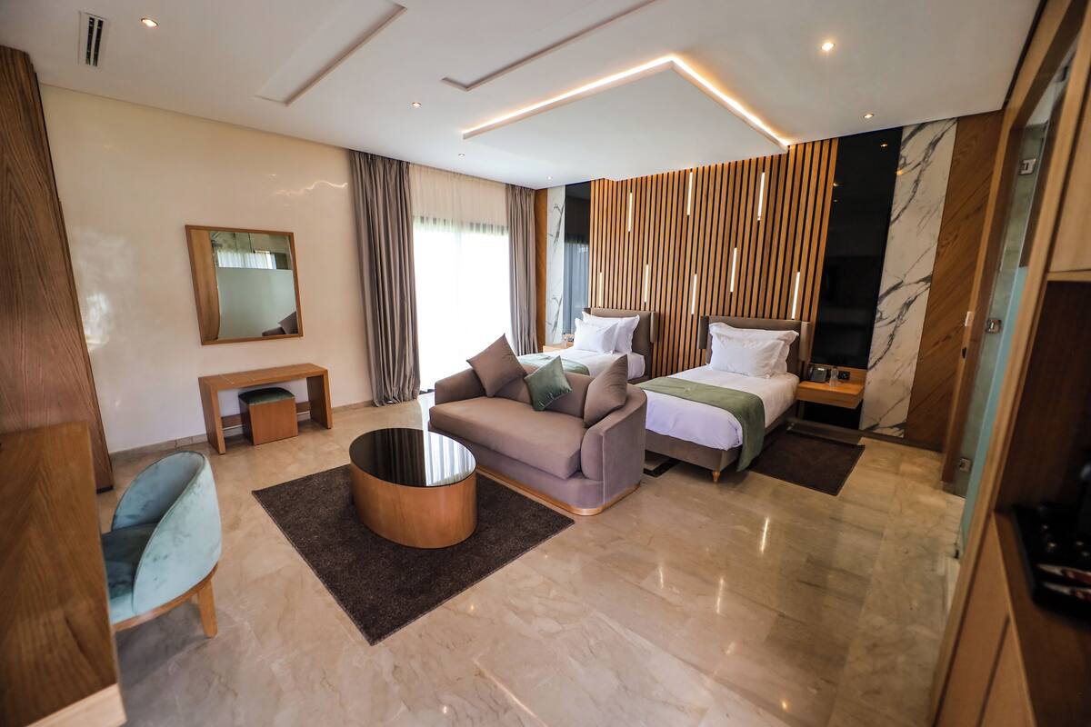 A modern hotel room with a sofa, a bed, a coffee table, and a mirror.