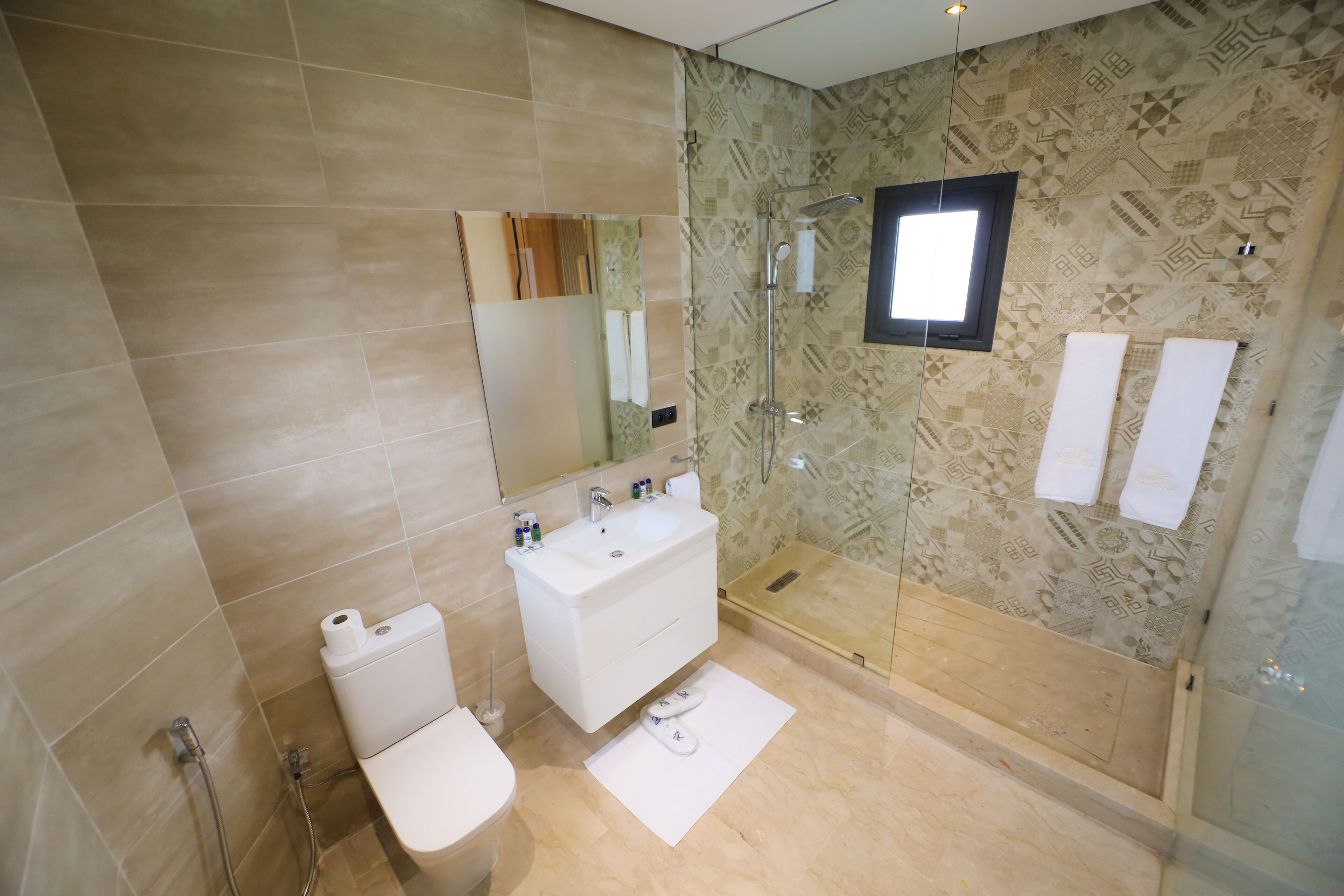 Un baño moderno con inodoro, lavamanos y zona de ducha.