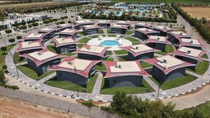 Un hôtel moderne à la conception circulaire, doté d’une piscine centrale, de nombreuses chambres et de jardins aménagés.