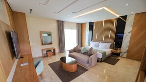 Une chambre d’hôtel moderne équipée d’un canapé, d’une table basse, d’un lit, d’une télévision et d’un bureau en bois.