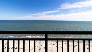 A beach view from a balcony with a railing, ocean, and beachgoers. - Unmatched Oceanfront Serenity on the 20th Floor (Myrtle Beach)
