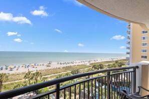 A balcony with a view of a beach, a pool, and a building with multiple floors. - Amazing: 5th Floor Oceanfront Two Bedroom (Myrtle Beach)