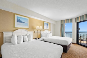 A hotel room with two beds, a nightstand, a lamp, and a view of the ocean. - Amazing: 5th Floor Oceanfront Two Bedroom (Myrtle Beach)
