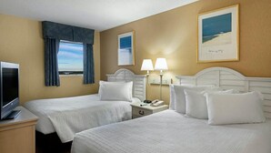 A hotel room with two beds, a TV, a nightstand, and a window with curtains. - Your Oceanfront Oasis 9th Floor 3 Bedroom Deluxe (Myrtle Beach)