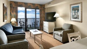 A hotel room with a balcony, a TV, a sofa, a chair, and a table. - Your Oceanfront Oasis 9th Floor 3 Bedroom Deluxe (Myrtle Beach)