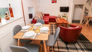 A modern living room with a dining area, red furniture, a television, and a red pendant light.