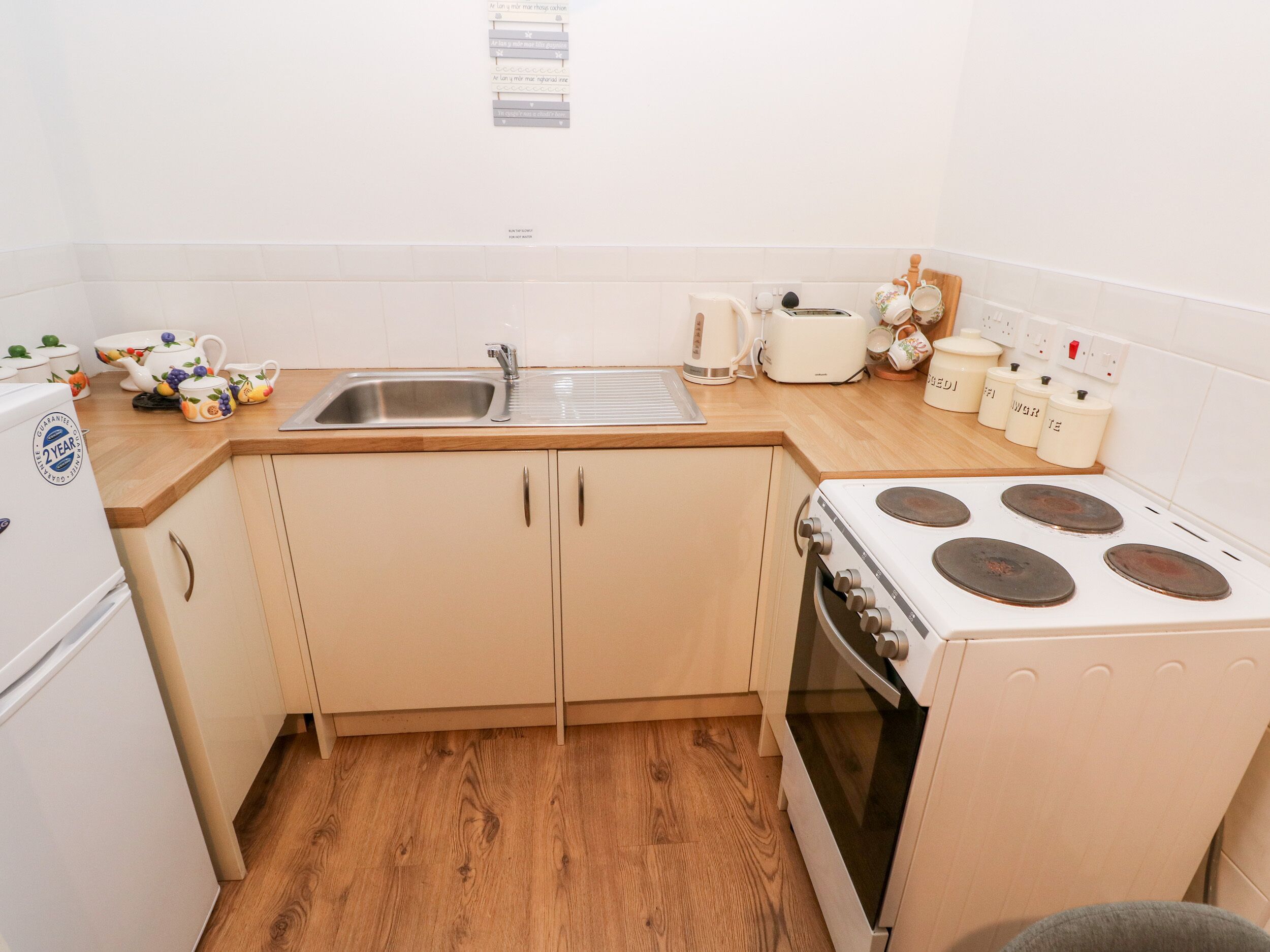 A compact kitchen with a sink, stove, and wooden countertop.