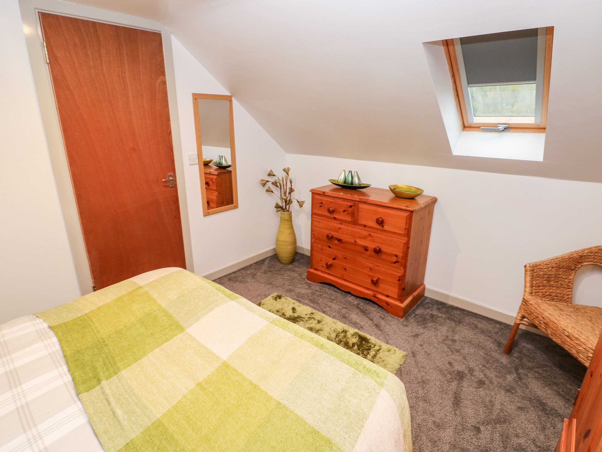 Une chambre à coucher avec un lit, une commode, un miroir, une fenêtre et une chaise.