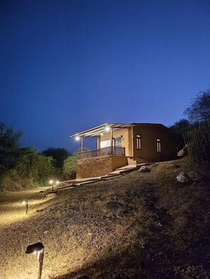 A small, single-story house with a porch, situated on a hillside. - Beyond Stay Jawai Legacy (Shivganj)