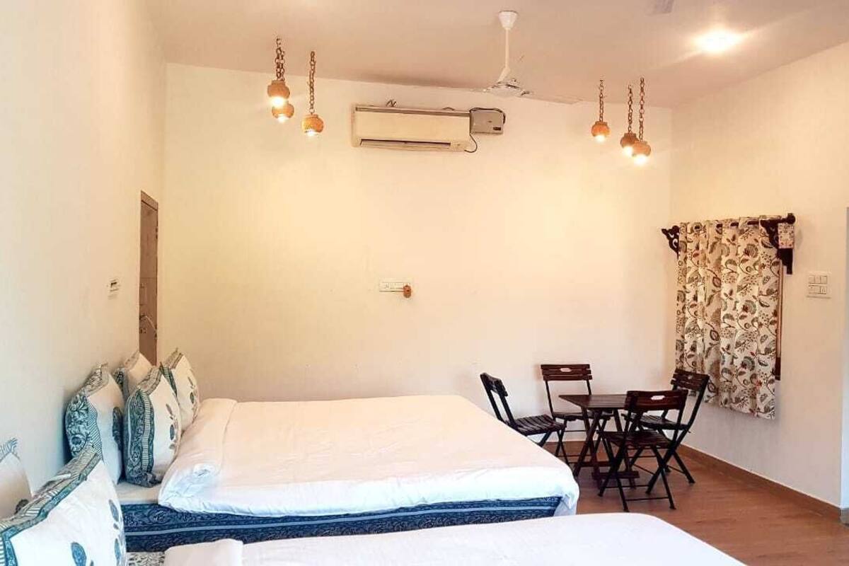 Un dormitorio con dos camas, una mesa de comedor, sillas, un aire acondicionado y un armario.