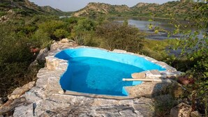 A stone swimming pool surrounded by natural landscape and hills. - Beyond Stay Jawai Legacy (Shivganj)