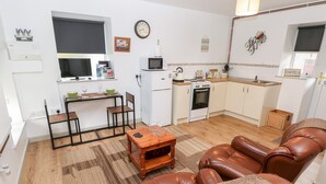 Ein kompakter Wohnbereich mit Küchenzeile, Essbereich und einer Sitzecke mit Ledersofas.