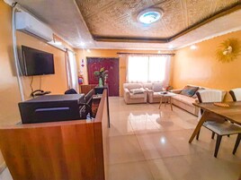 Una sala de estar con televisión, sofá y mesa de comedor.