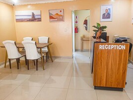 A reception area with a wooden desk labeled "RECEPTION," a dining table with chairs, and framed artwork on the walls.
