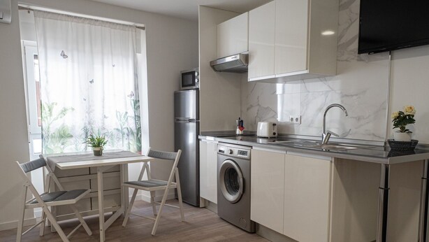 Une cuisine compacte équipée d’un lave-linge, d’un four à micro-ondes et d’un évier.