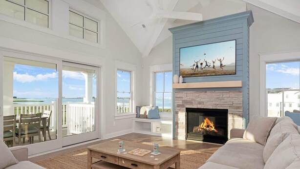 Amplia sala de estar con chimenea, ventanas grandes y vista al océano.
