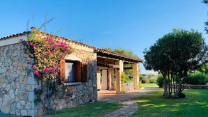 A stone building with a covered patio and a garden. - 3 bedroom villa in sardinia (Sardegna)