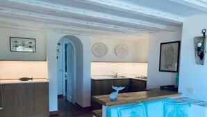 A modern kitchen with a wooden countertop and a sink, a blue sofa with decorative pillows, and a framed map on the wall. - 3 bedroom villa in sardinia (Sardegna)