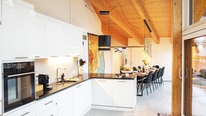 A modern kitchen with white cabinets, a central island, and a dining area with a table and chairs.