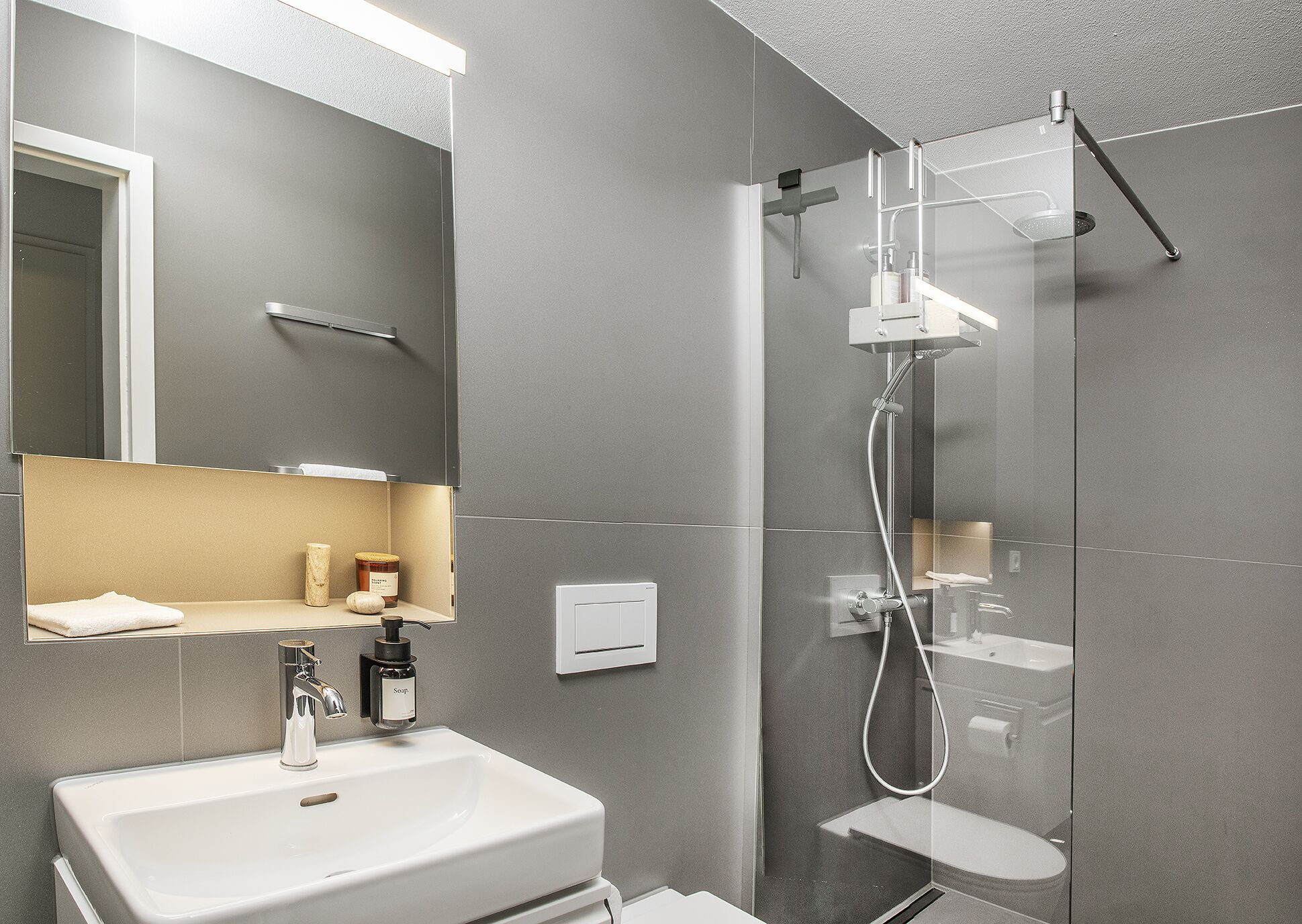 Une salle de bain moderne avec une douche à parois de verre, un lavabo blanc et un miroir au-dessus du lavabo.