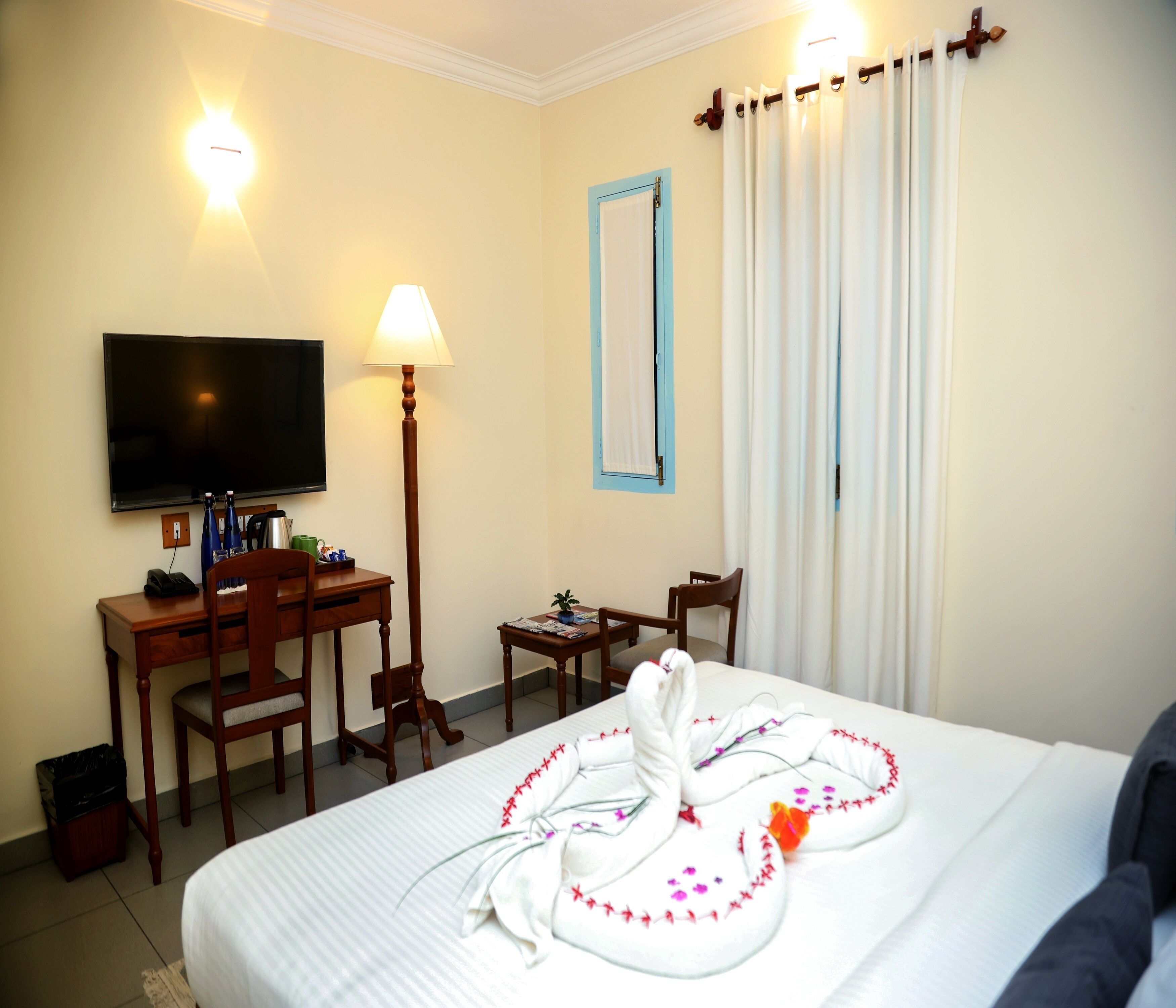 A hotel room with a bed, a desk, a chair, a television, and a window with curtains.