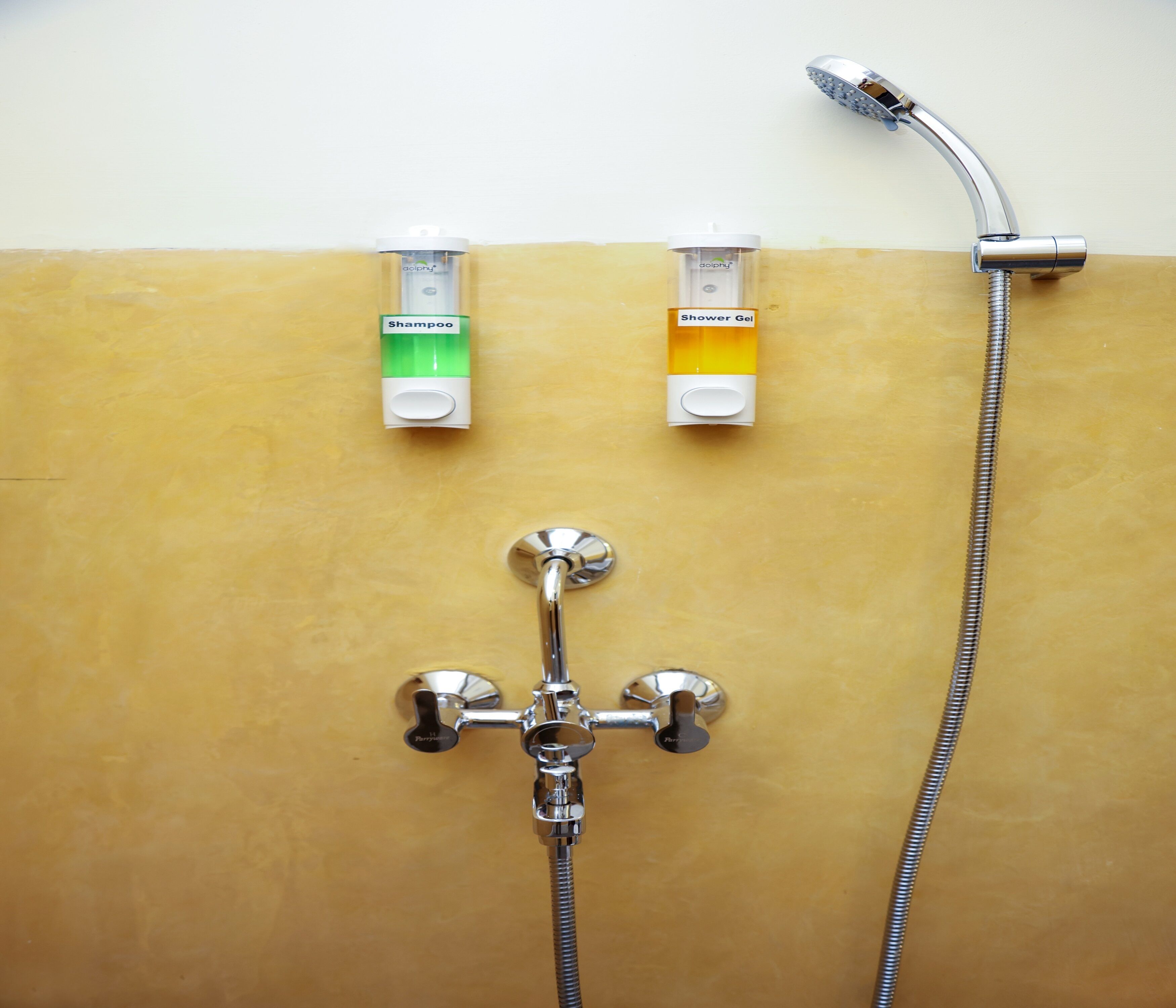 Un baño con ducha, dos dispensadores de champú y un dispensador de gel de ducha.