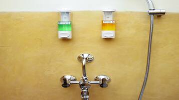 Un baño con ducha, dos dispensadores de champú y un dispensador de gel de ducha.