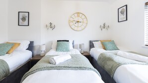 Een hotelkamer met twee bedden, een wandklok en kunstwerken in lijsten.